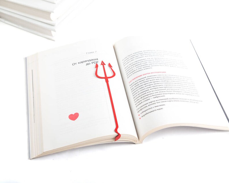 May include: A red plastic bookmark shaped like a trident with a small red heart on the page. The bookmark is in an open book with the text "От карандаша до PDF" on the page.