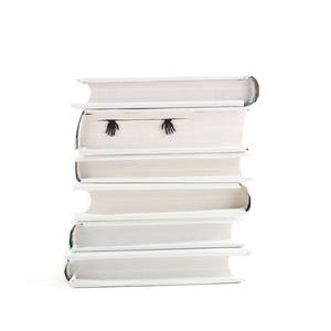 Hands of the skeleton bookmark on the side of the book. Black flat metal bookmark Skeleton in the book.