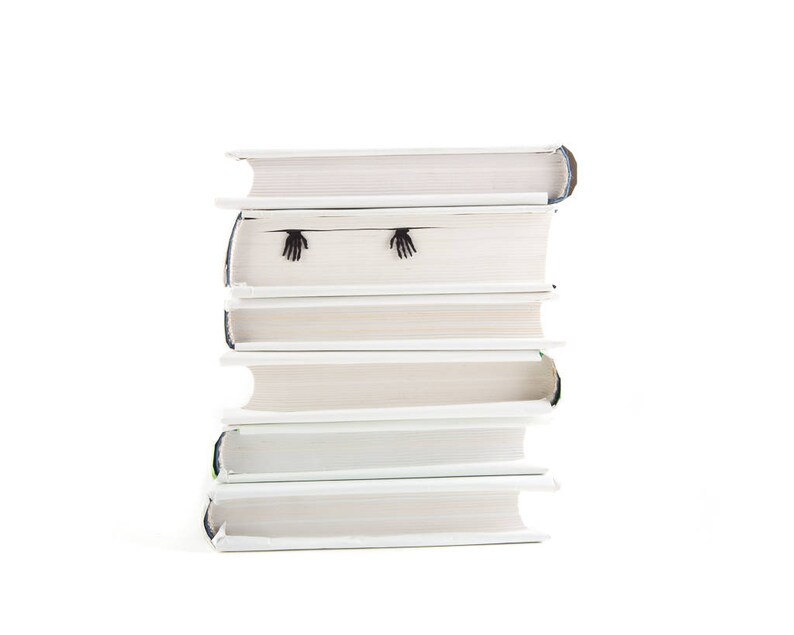 Hands of the skeleton bookmark on the side of the book. Black flat metal bookmark Skeleton in the book.