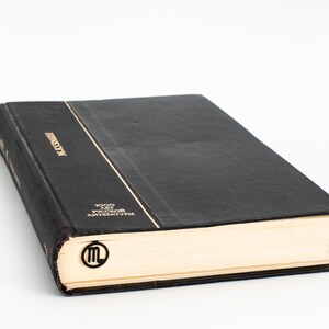 May include: A black hardcover book with gold lettering on the spine that reads "LITERATURE" and "1000 лет русской литературы". A gold bookmark with the letter "M" is on the page.