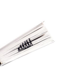 May include: A book with a black bookmark shaped like a line of stick figures representing the evolution of humans.