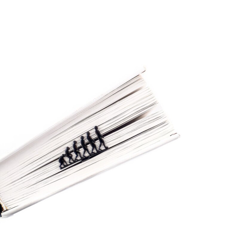 May include: A book with a black bookmark shaped like a line of stick figures representing the evolution of humans.