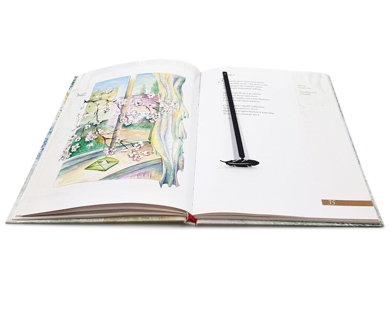 May include: An open book with a black feather bookmark. The book has a watercolor illustration of a window with a blooming tree branch and a green envelope on the left page. The right page has text and the number 35.