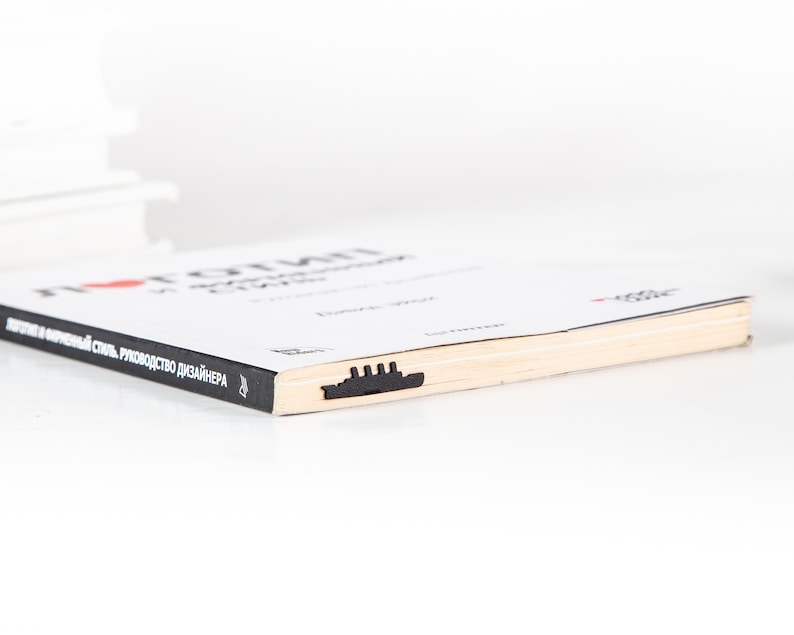 May include: A white book with the title "I love origami" and the text "Japanese paper folding, a guide for designers" on the cover. The book has a black bookmark shaped like a ship.