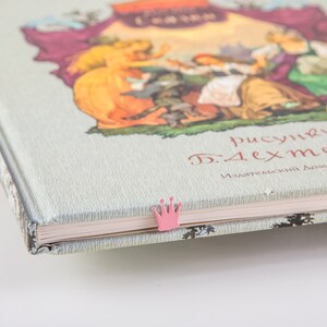 A closed book with a pink crown bookmark.