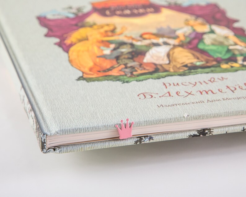 A closed book with a pink crown bookmark.