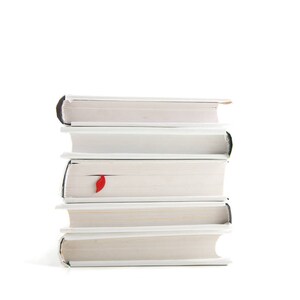 May include: A stack of five white books with a red bookmark sticking out of the top book.