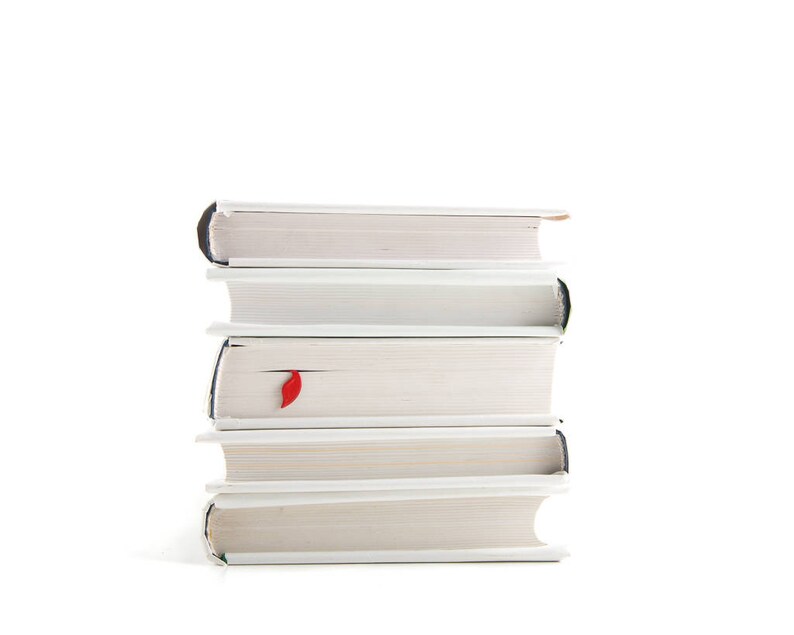 May include: A stack of five white books with a red bookmark sticking out of the top book.