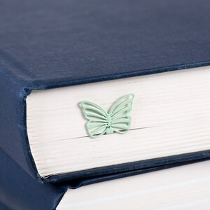 May include: A stack of navy blue hardcover books with a light green butterfly bookmark on the top book.