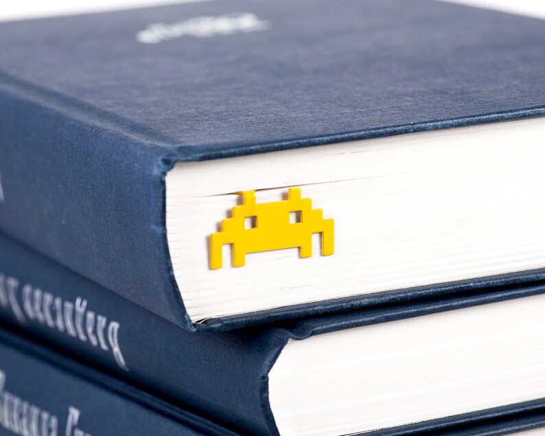 Yellow metal bookmark Retro Monster. A flat metal stick stays between the pages of the book. The monster is on the side of the book.  It is visible even when the book is closed. Made in our workshop in Ukraine. Not mass manufactured.