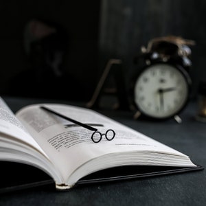 Black metal bookmark. Nerdy round eyeglasses bookmark - a perfect gift for avid readers. A long flat stick stays between the pages of the book. The round eyeglasses are on the side of the book. They are visible even when the book is closed.