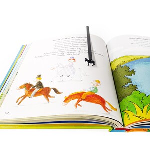 Black donkey bookmark in open illustrated poetry book on stacked books