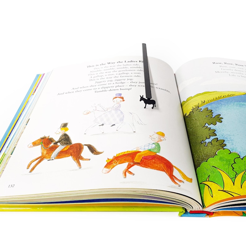 Black donkey bookmark in open illustrated poetry book on stacked books