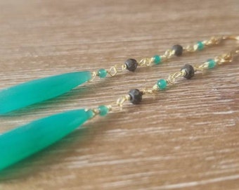 Pode incluir: Um par de brincos longos de turquesa em forma de lágrima com fio de ouro e contas pretas.
