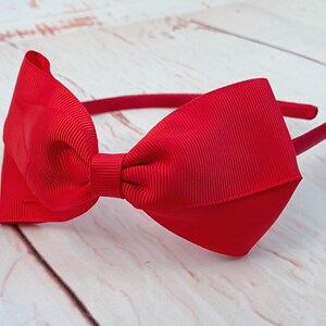 May include: A red ribbon headband with a large bow. The headband is made of a soft, flexible material and is perfect for adding a touch of style to any outfit.