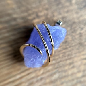 May include: A purple amethyst crystal wrapped in a gold wire spiral.