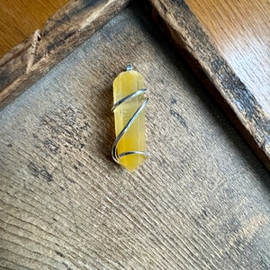 Pu&ograve; includere: Un ciondolo in cristallo di citrino giallo avvolto in filo d'argento.