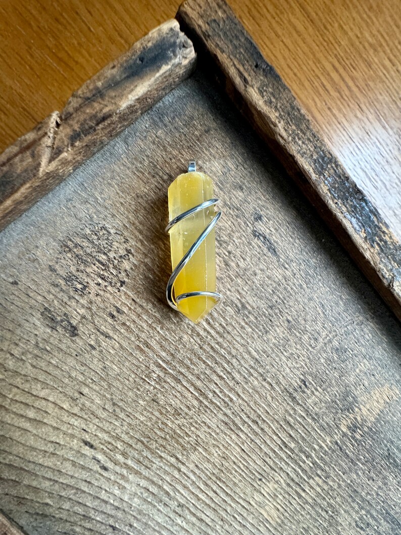 Pu&ograve; includere: Un ciondolo in cristallo di citrino giallo avvolto in filo d'argento.