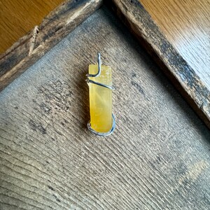 Pu&ograve; includere: Un cristallo di citrino giallo avvolto in filo d'argento, pronto per essere trasformato in un ciondolo.