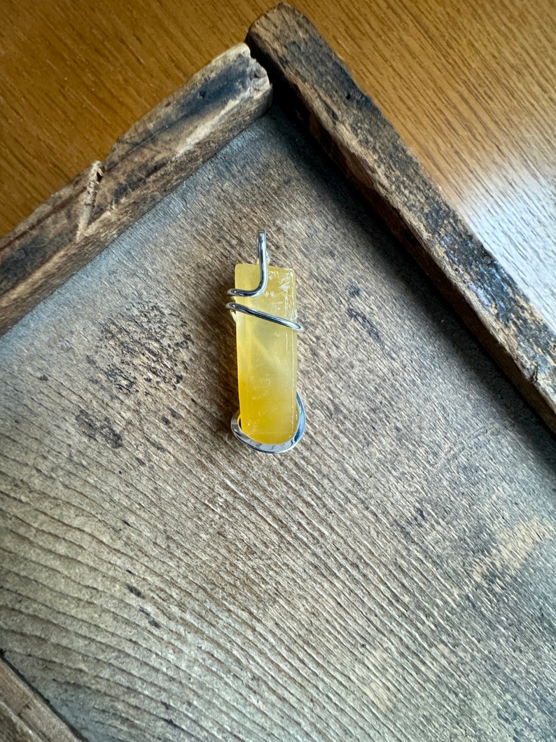 Pu&ograve; includere: Un cristallo di citrino giallo avvolto in filo d'argento, pronto per essere trasformato in un ciondolo.