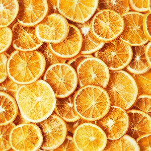 May include: A close-up image of a pile of dried orange slices. The orange slices are arranged in a random pattern and are all a vibrant orange colour.