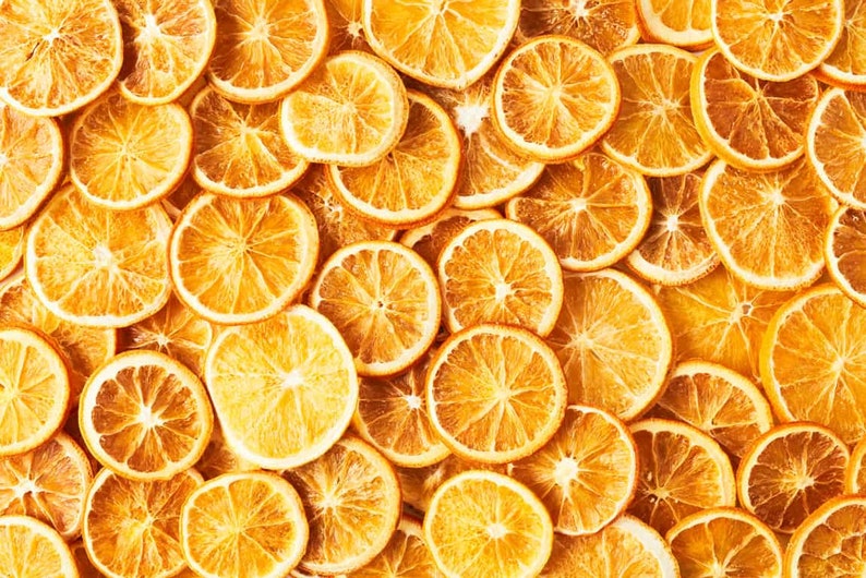 May include: A close-up image of a pile of dried orange slices. The orange slices are arranged in a random pattern and are all a vibrant orange colour.