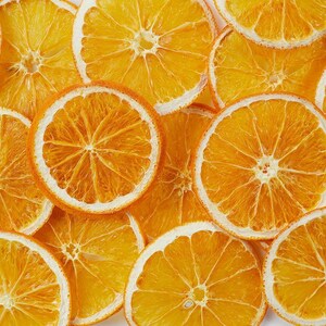 May include: Dried orange slices, a natural, rustic, and decorative element. The slices are arranged in a close-up, showcasing their vibrant orange colour and intricate texture.