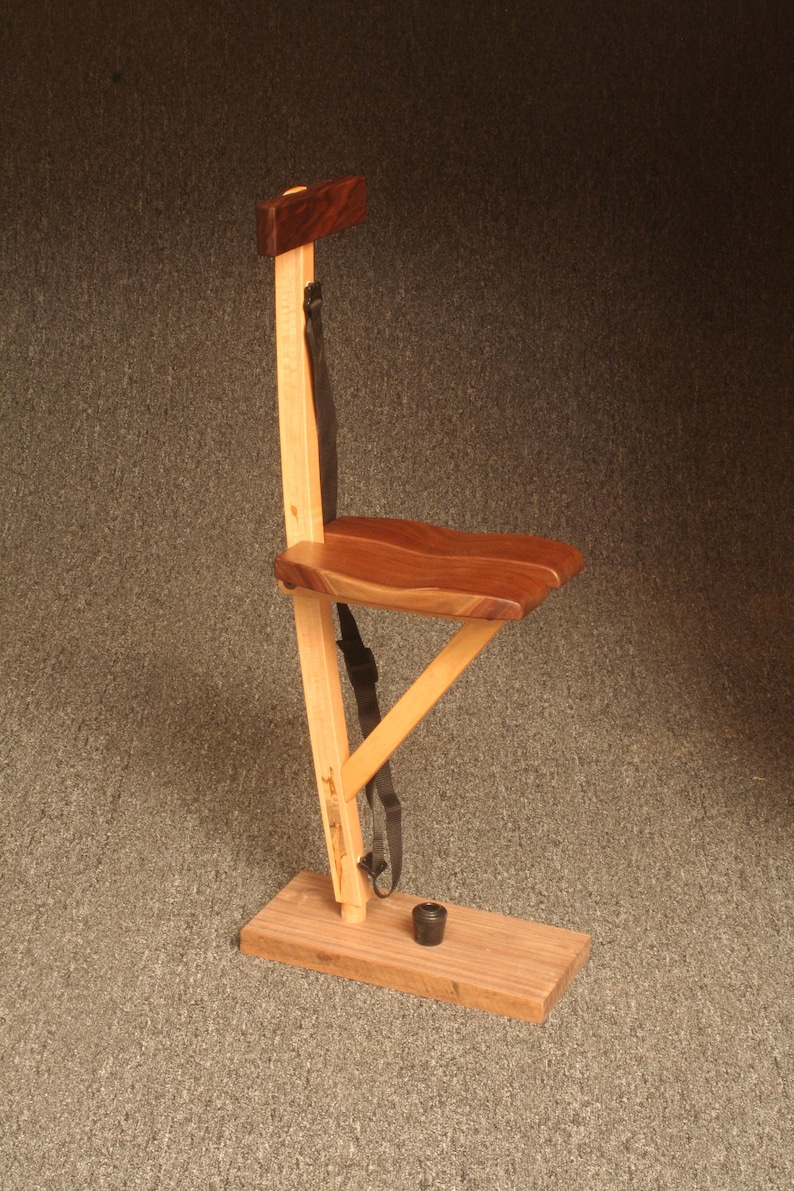 May include: A wooden folding chair with a brown seat and a black strap. The chair is made of light and dark wood and has a simple design.