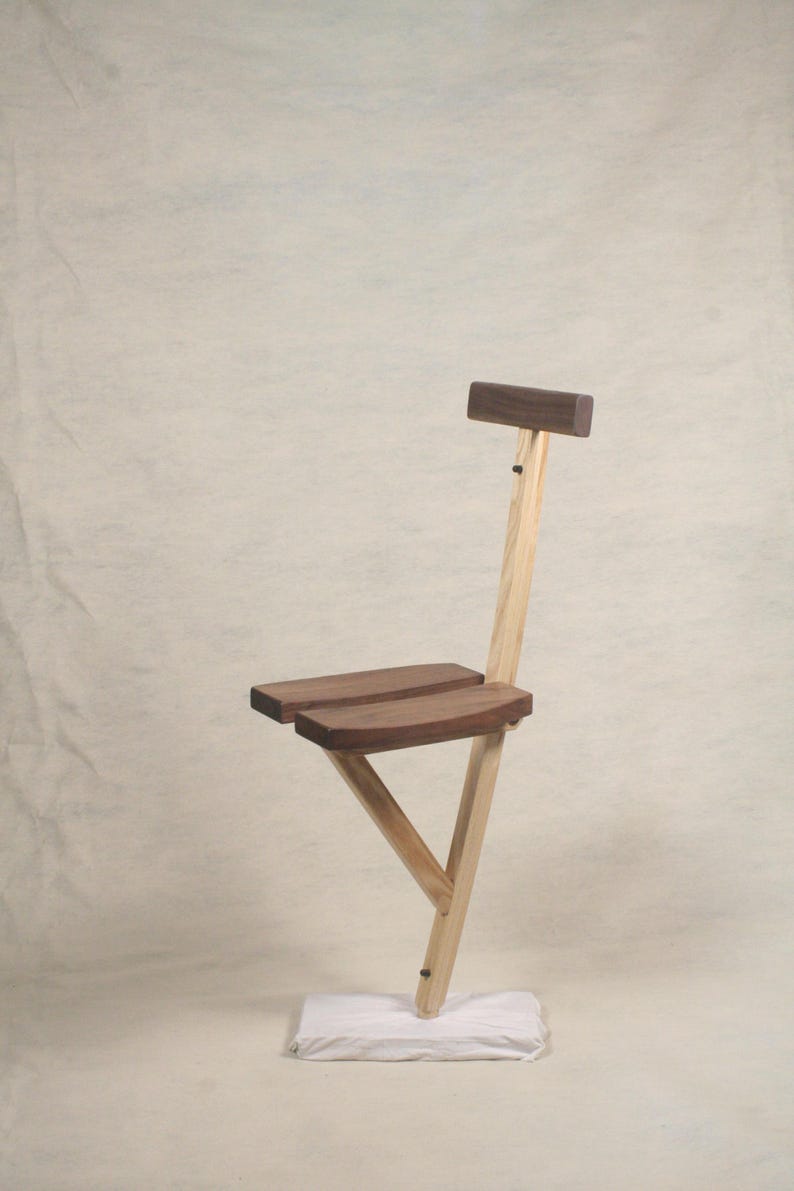 May include: A wooden chair with a simple design. The chair has a dark brown seat and a light brown frame. The chair is standing on a white surface.
