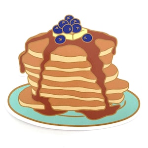 May include: A stack of pancakes with a brown syrup drizzle and blueberries on top, served on a light blue plate.