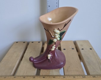May include: A vintage, ceramic vase in a horn shape, featuring a peach-colored interior and a deep burgundy base. The vase is adorned with white floral accents and brown branch details. The vase measures approximately 8 inches in height.