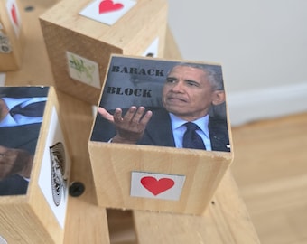 May include: Wooden blocks with printed images and text. One block features a picture of Barack Obama with the text "BARACK BLOCK". Other blocks have heart and floral designs.