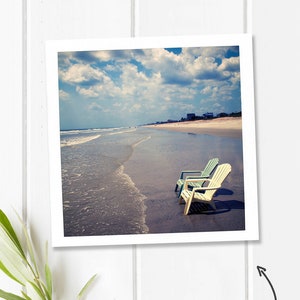 Peut inclure: Impression d'art imprimable repr&eacute;sentant une sc&egrave;ne de plage avec deux chaises blanches et bleues sur le sable. Le ciel est bleu avec des nuages blancs. Le texte "Instant Printable Home Decor!" est &eacute;crit sur l'image.