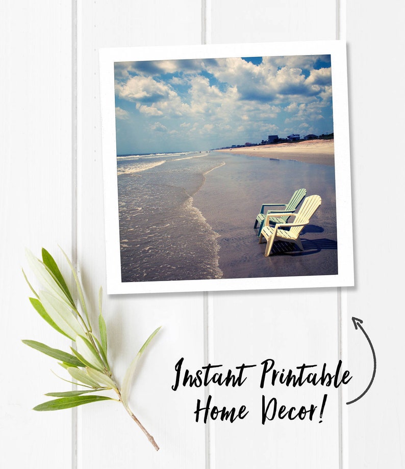 Peut inclure: Impression d'art imprimable repr&eacute;sentant une sc&egrave;ne de plage avec deux chaises blanches et bleues sur le sable. Le ciel est bleu avec des nuages blancs. Le texte "Instant Printable Home Decor!" est &eacute;crit sur l'image.