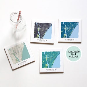 May include: Four square ceramic coasters featuring a map of Wilmington, North Carolina in different color schemes. The text "WILMINGTON, NC" and coordinates are printed on each coaster. The text "Available in 4 colors!" is printed on a white circle.