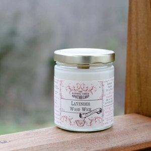 Puede incluir: Un tarro de vela blanco con tapa dorada y una etiqueta que dice "The Natural Choice Apothecary Lavender Wood Wick".