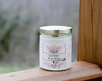 May include: A white candle jar with a gold lid and a label that reads "The Natural Choice Apothecary Lavender Wood Wick".