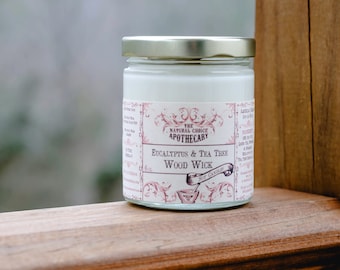 Puede incluir: Una vela de vidrio en un frasco con una etiqueta blanca que dice "The Natural Choice Apothecary Eucalyptus & Tea Tree Wood Wick". El frasco está sobre una superficie de madera.