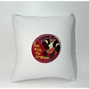 Peut inclure: Un badge rond avec un fond rouge à texture mouchetée. Le badge représente un personnage de gorille de dessin animé portant une chemise blanche, accompagné du texte "Who Framed Roger Rabbit" et "Get with the program!" en lettres jaunes.
