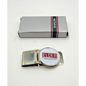 May include: A silver-toned money clip with a circular emblem featuring the text "ELDER OIL TOOLS" and a box with the word "BARLOW" printed on it. The money clip is open, and the box is closed.