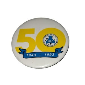 Pode incluir: Botão branco com um "50" amarelo e um círculo amarelo com texto e uma faixa azul que diz "1943 - 1993". O botão também tem o texto "Minneapolis Saint Paul Metropolitan Airports Commission MAC".