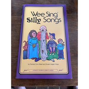 May include: A children's book titled "Wee Sing Silly Songs" with a colorful illustration of cartoon characters. The cover has a purple border and the text "A PRICE STERN SLOAN CLASSIC".