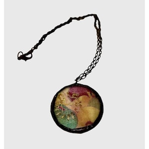 May include: A round pendant necklace with a colorful fabric design and a black chain.