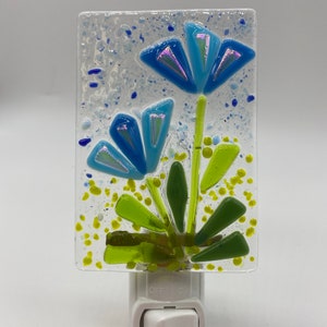 May include: A blue and green stained glass nightlight with a floral design. The nightlight has an on/off switch.