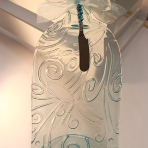 May include: A clear glass serving tray with a dragonfly design and a blue ribbon. The tray has a small indentation for a butter knife, which is included.
