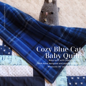 May include: Cozy Blue Cat Baby Quilt, a blue and white plaid baby quilt with a fleece backing. The quilt measures 36 inches square and features a cute gray crocheted cat toy.