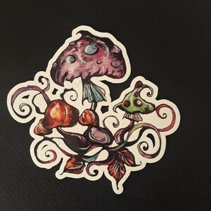 Peut inclure: Un autocollant coloré représentant une illustration fantaisiste de champignons avec des vignes et des feuilles en spirale. Les champignons sont peints dans des tons de rose, rouge, vert et violet.