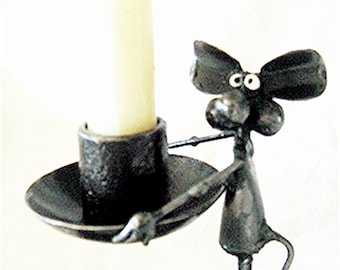 May include: A black metal candle holder shaped like a mouse holding a candle in its front paws. The mouse has large ears and googly eyes.