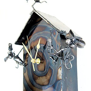 May include: A metal clock shaped like a house with a sign that says "it's wine o'clock!" and three mice figures holding wine bottles. The clock face has a swirling pattern and gold hands.