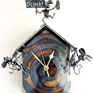 May include: A metal wall clock with a whimsical design featuring a mouse holding a bottle of wine and a sign that reads "It's Wine O'Clock!" The clock face is a circular, swirling pattern of blue and brown metal.